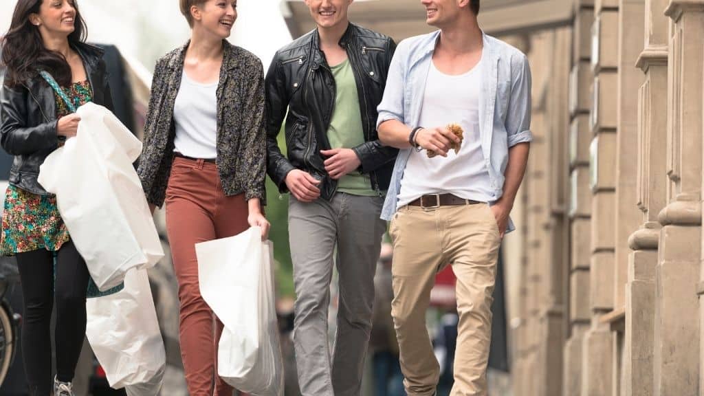 four friends walking on street with bags