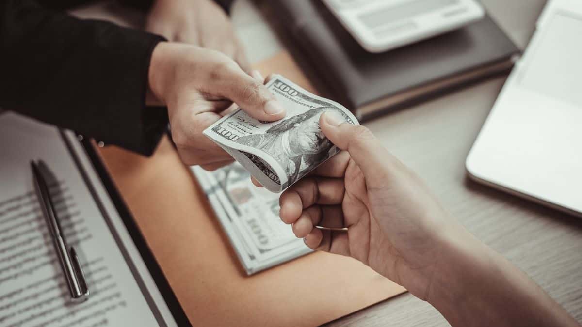 hands exchanging money over desk
