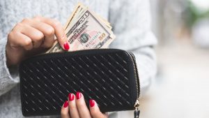 hands holding black wallet with cash
