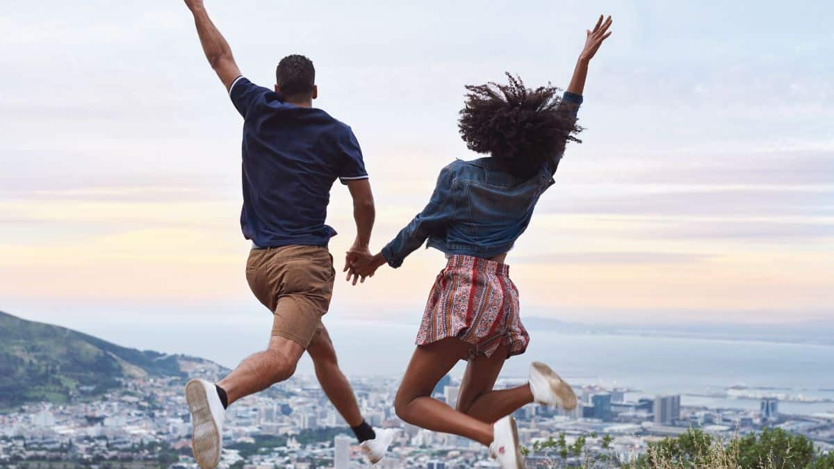 two people holding hands jumping over city