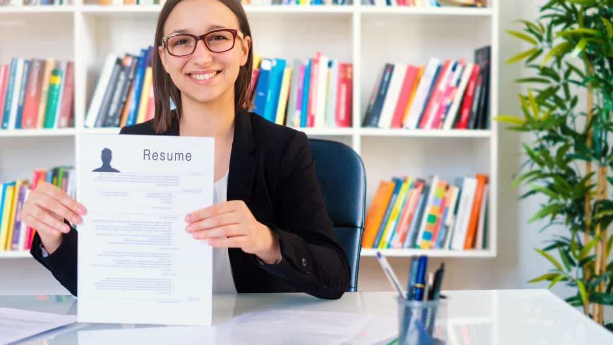 woman holding resume in front of bookshelf