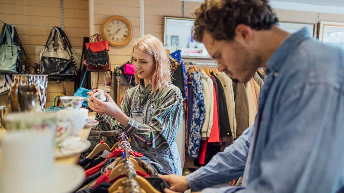 man and woman browsing thrift shop clothing racks