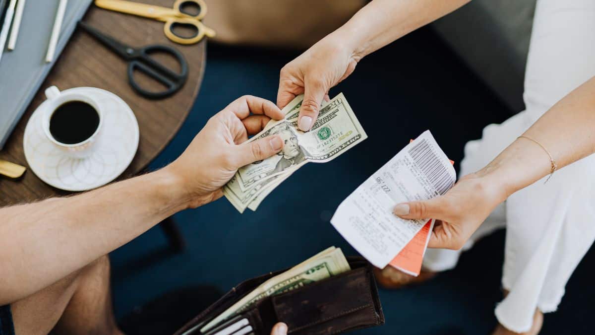 hands exchanging cash from wallet for paper receipt